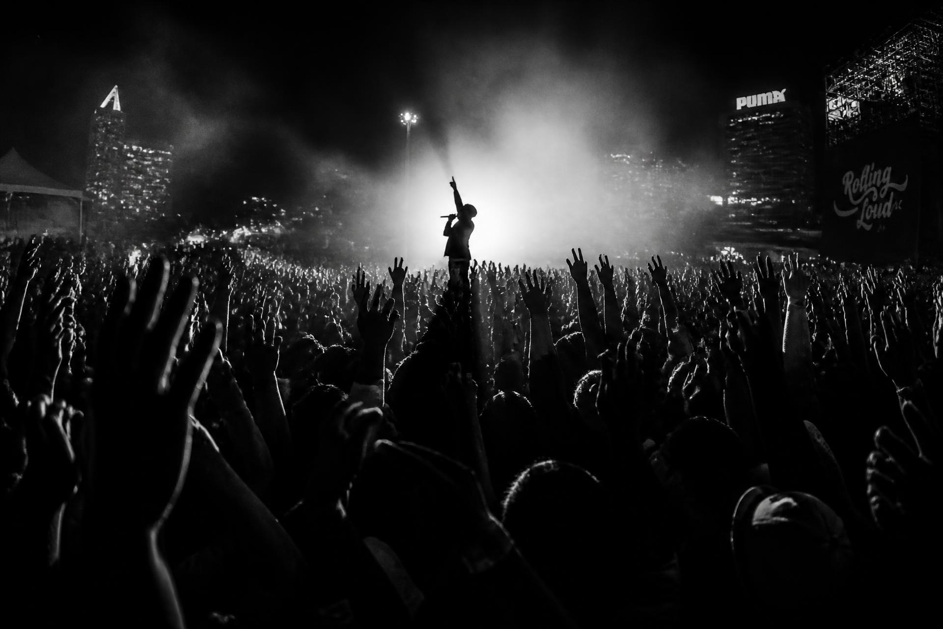 Público de um show de rap com as mãos erguidas em frente ao palco